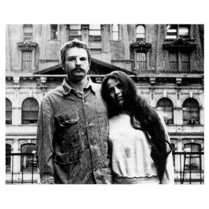 Black and white photo of Eva Hesse on the right and Tom Doyle on the left with New York City buildings in the background.